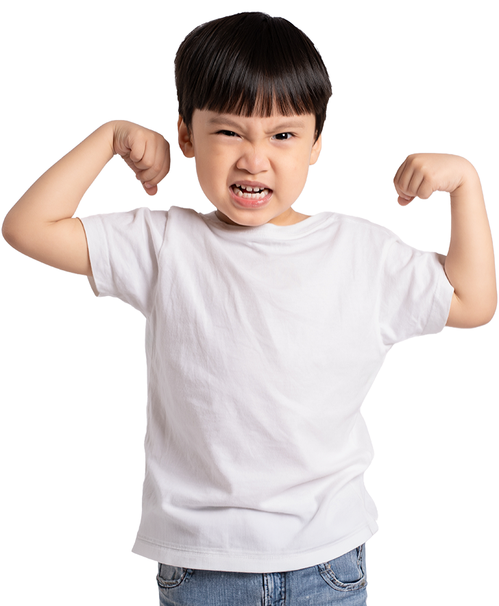 Young boy in a white t-shirt and jeans confidently flexes his biceps against a black background, playfully showing strength with a determined expression.