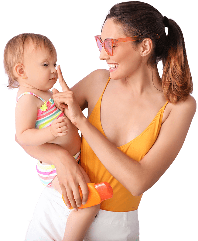 A smiling woman in an orange swimsuit playfully applies sunscreen to a baby in a striped swimsuit. She holds a sunscreen bottle