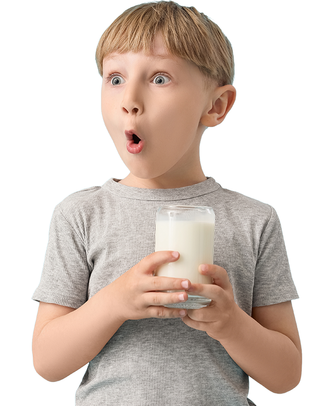 A surprised child with wide eyes and an open mouth holds a glass of milk with both hands. The background is black, highlighting the child's expression.